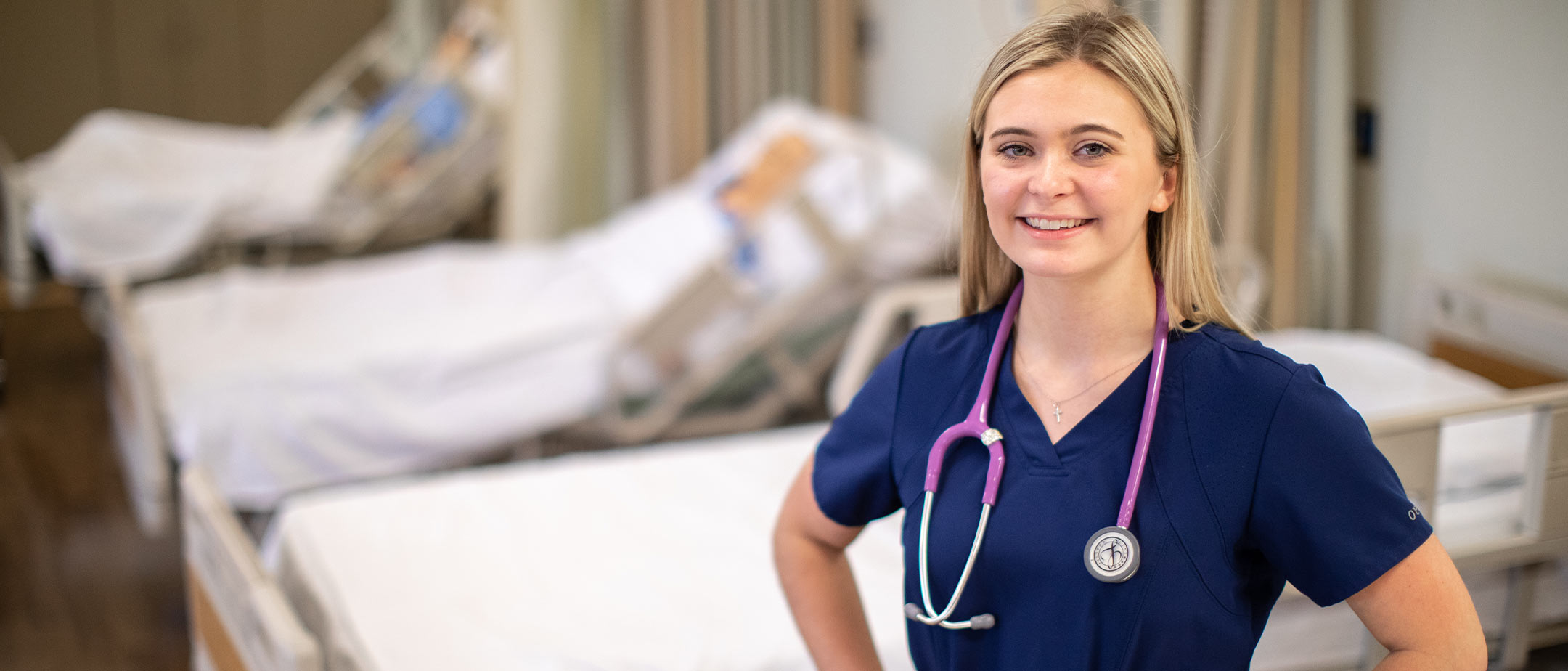 A nursing student standing in a simulation lab