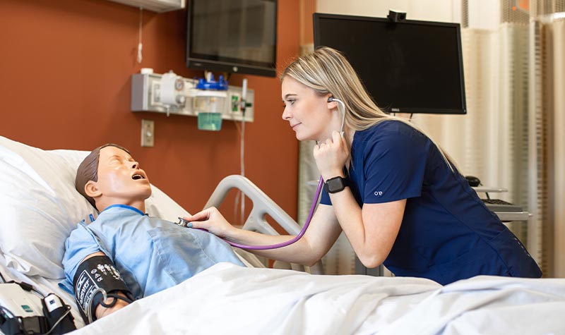 Nursing students practicing on a mock patient