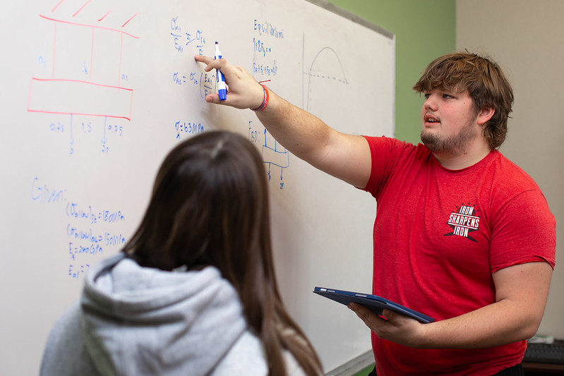 SI leader explains math equation at whiteboard