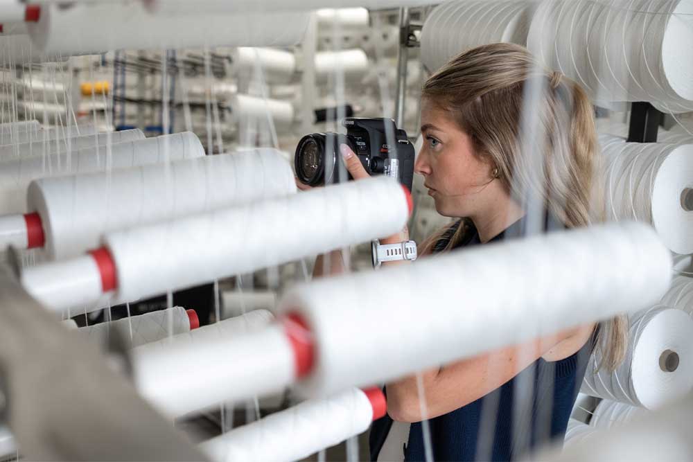 PennWest student photographs textile production equipment during a hands-on research and creative project that applies classroom learning to real-world experiences.