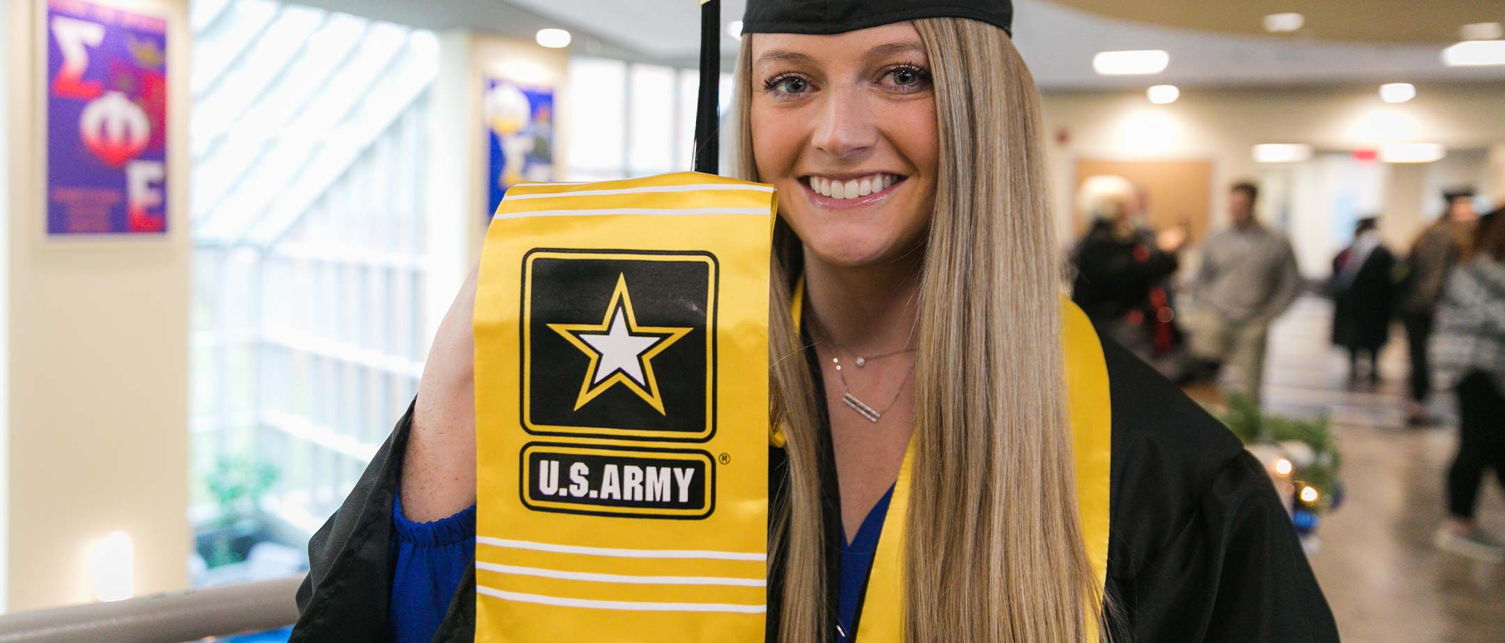 A military graduate holding her Army sash