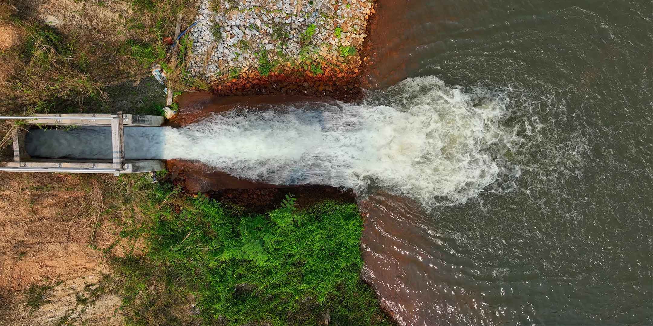 water flowing through a concrete irrigation channel into a reservoir