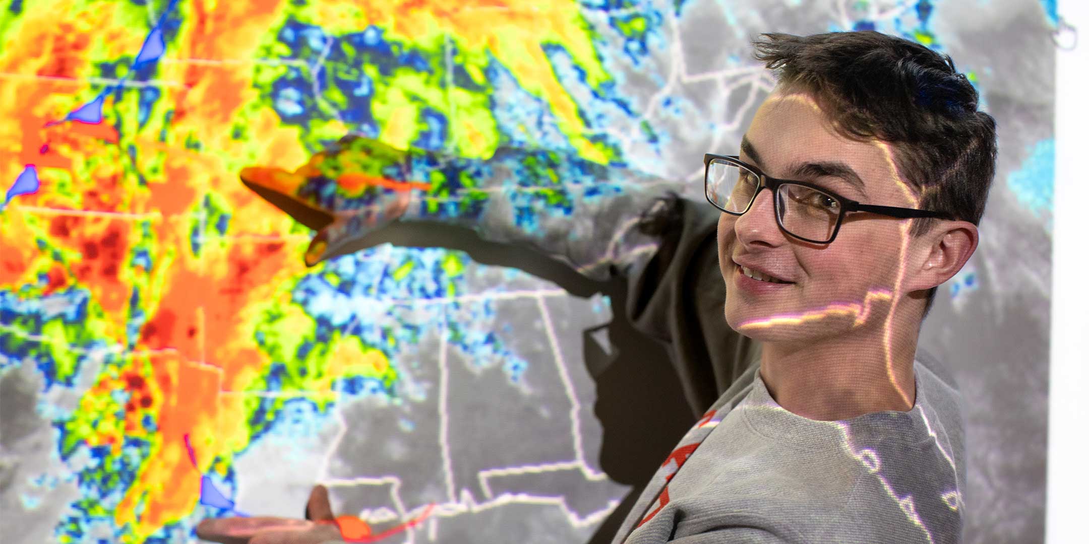 a weather and climate risk management student pointing to a location projected on a screen