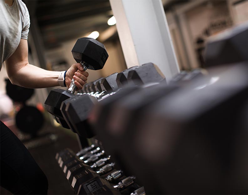 An athletic trainer selecting a dumbbell from a weight rack
