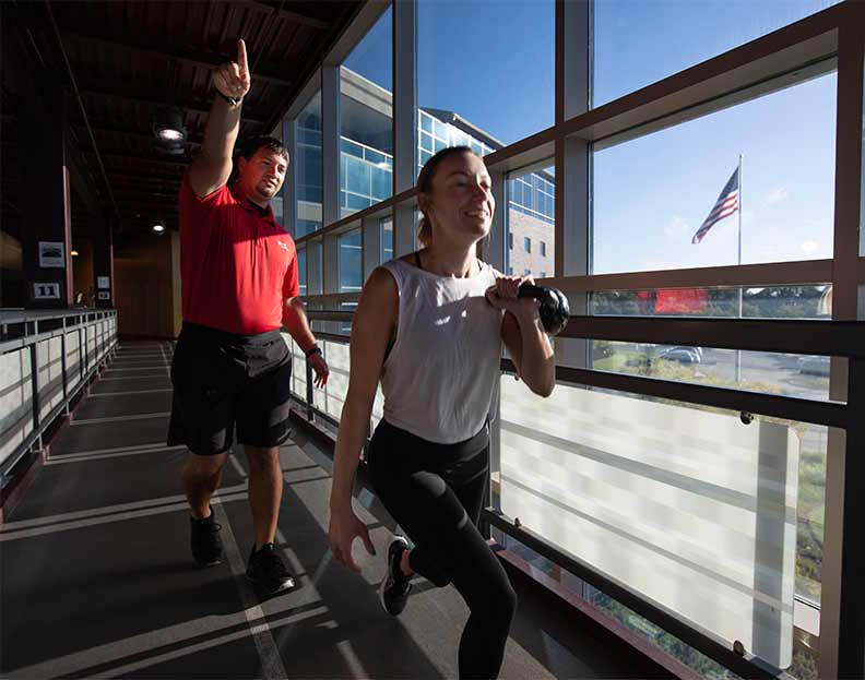 a pre-athletic training student encouraging a student-athlete during a workout