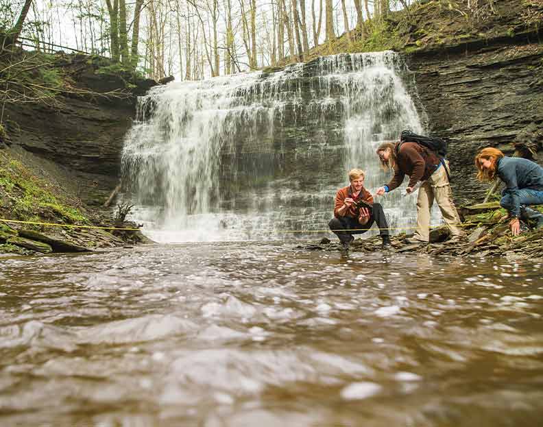 geotechnical applications students taking a water sample from a local stream