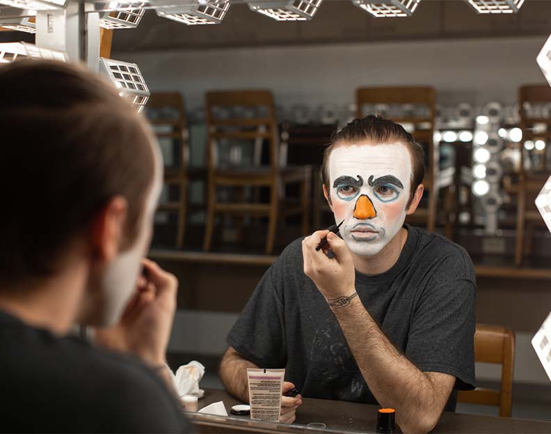 a performing arts students applying makeup before a play