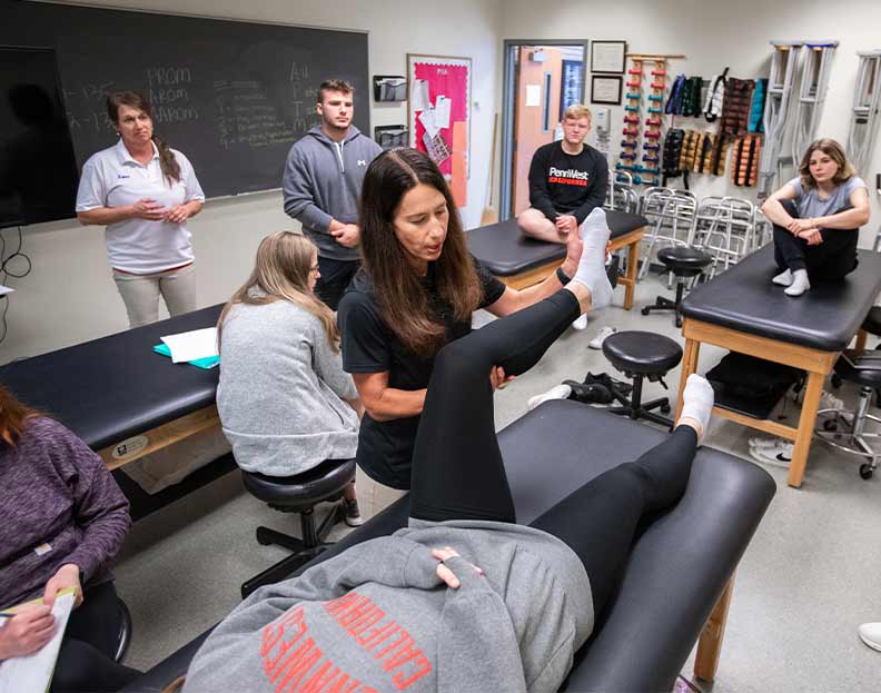 physical therapy students learning about proper leg movement in a classroom