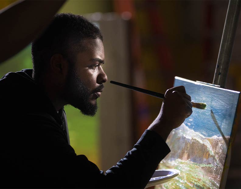 a visual art student painting on a canvas
