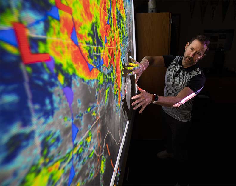 a weather and climate risk management professor explaining weather patterns on a projector screen