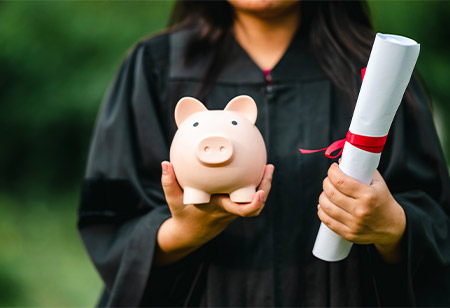 A graduate student holding a diploma and piggy bank