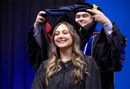 A graduate student receiving their sash