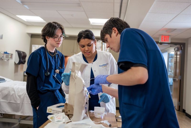 Three nursing students practice with a picc line simulation