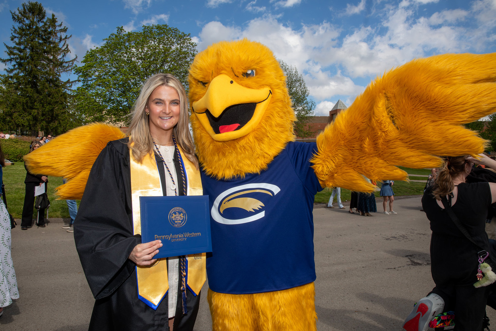 PennWest Clarion student speaker Caleigh Aigler poses with Ernie the Eagle following commencement on May 9, 2026