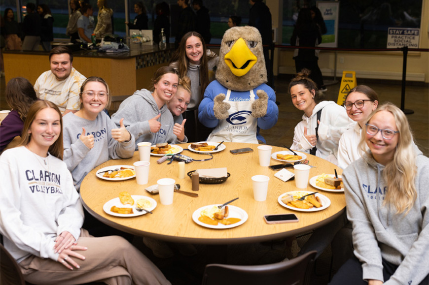 Clarion students eating with Ernie the Eagle