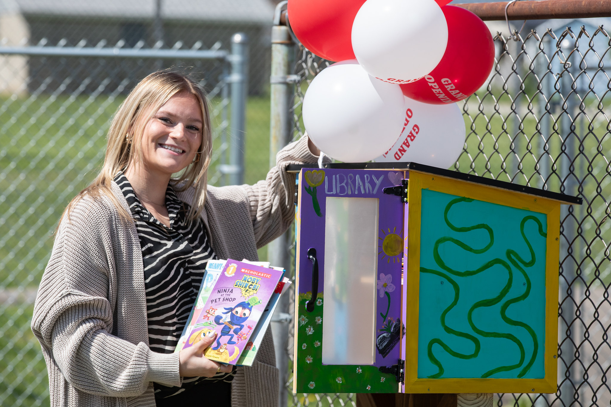 student stands beside donated free library