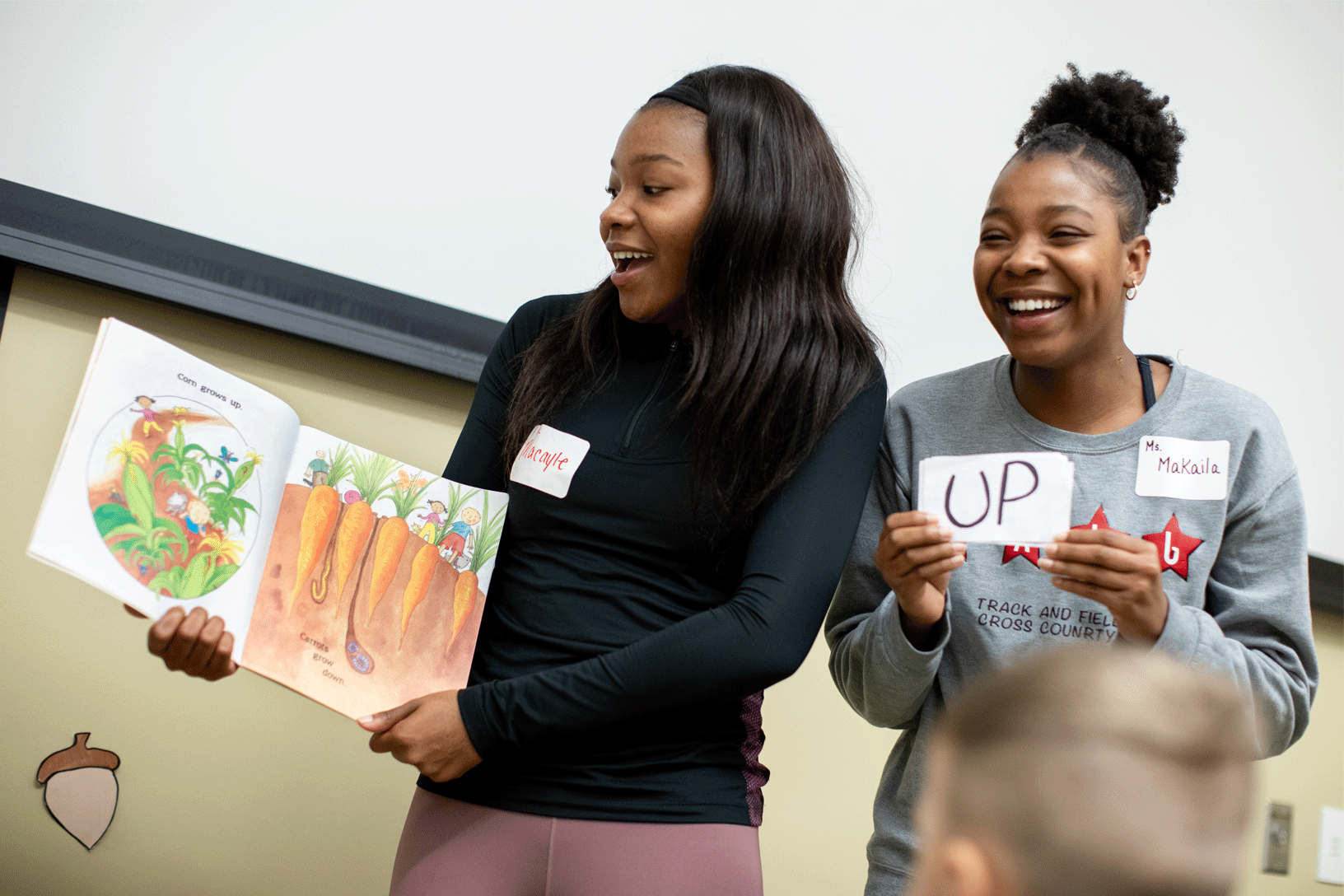 Macayle Wade, left, and Makaila Wade, both senior early childhood education majors, read an interactive book to preschoolers.