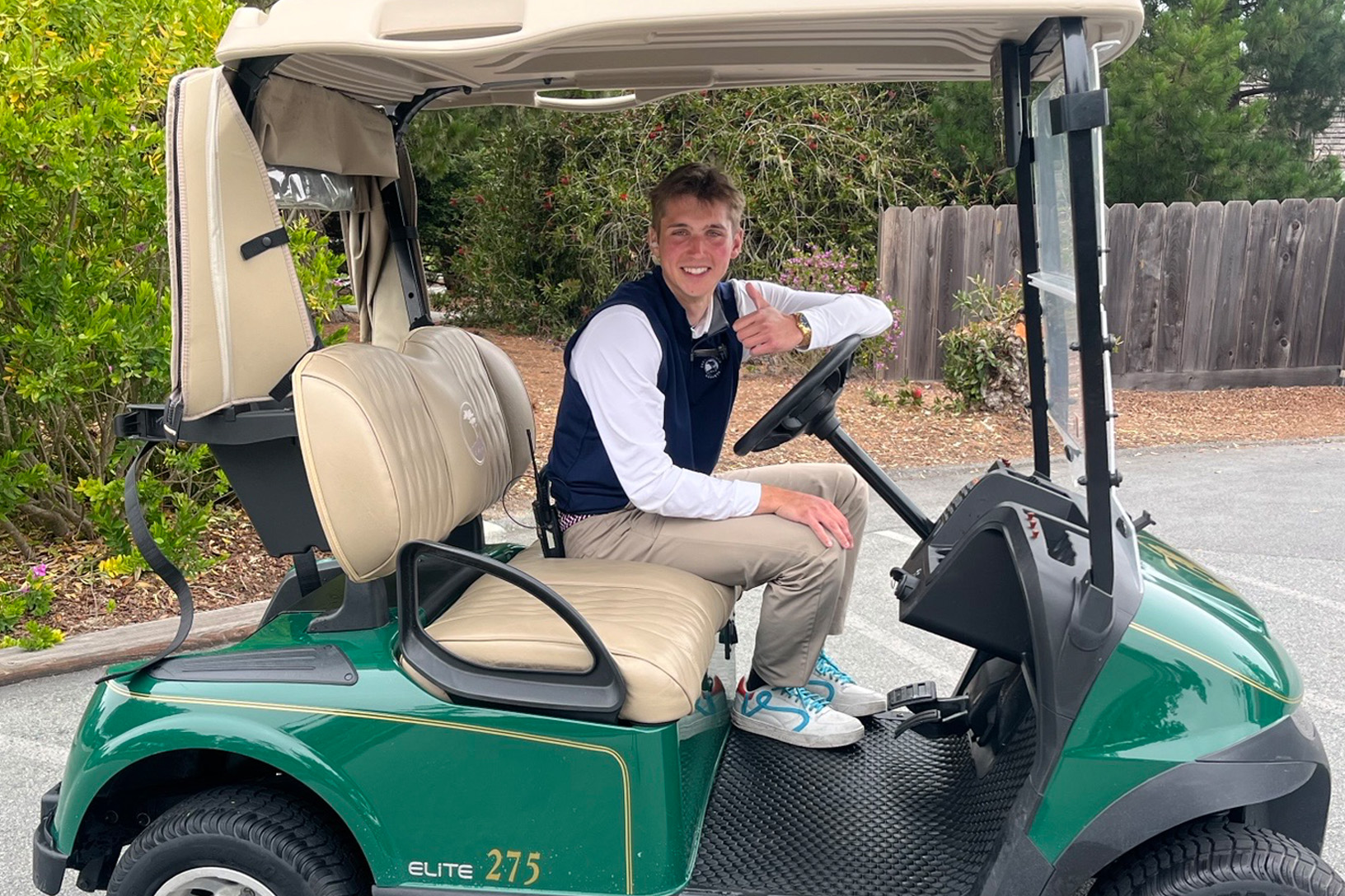 Cal Koukides poses for a photo in a golf cart during his internship at Pebble Beach.