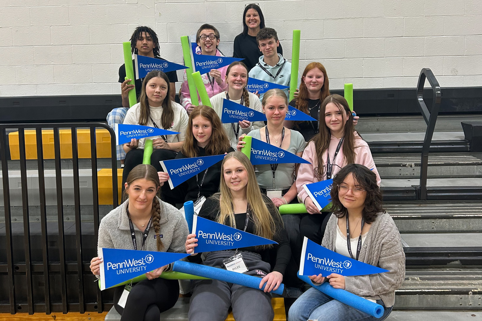 students sit on bleachers with PennWest pennants